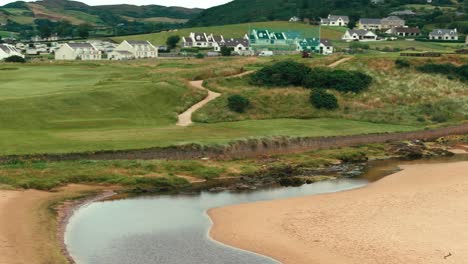 drone orbit along coastline of iconic ireland links green golf course showing landscape and cart path through rolling irish hills