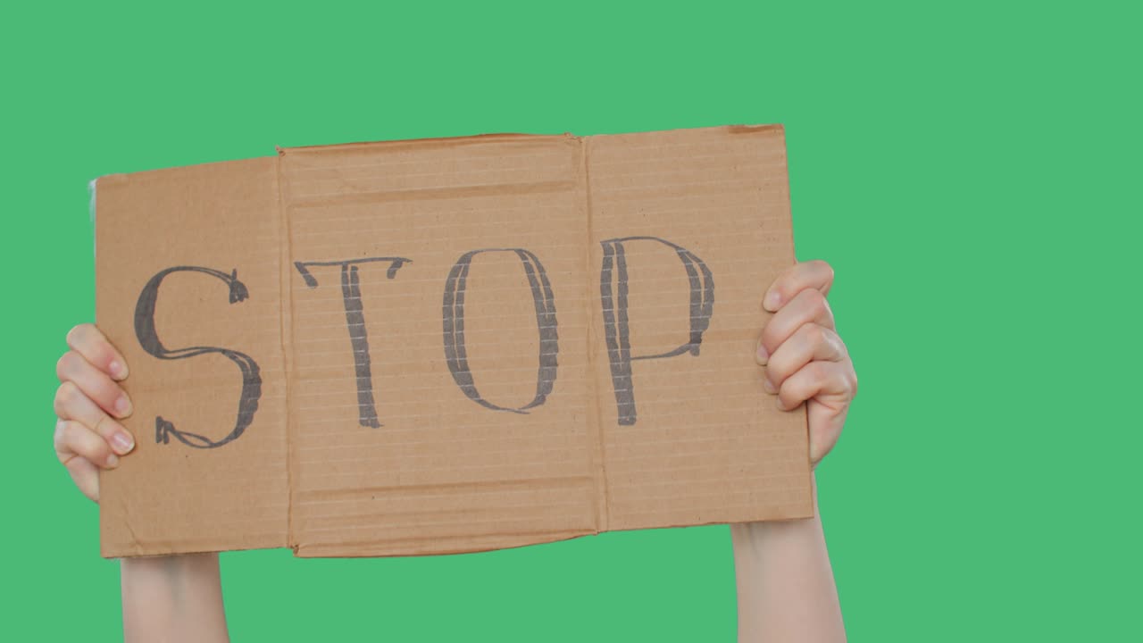 시위대 는 초록색 배경 에 있는 손 에 스 카드보드 표지판 을 들고 있다