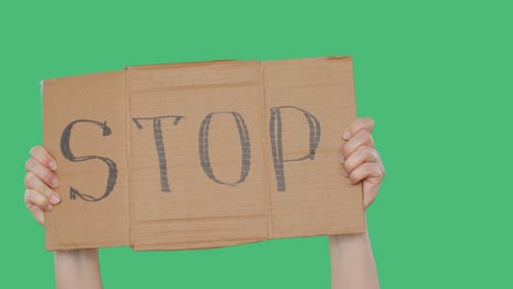 protester holding stop cardboard sign in hands on green background