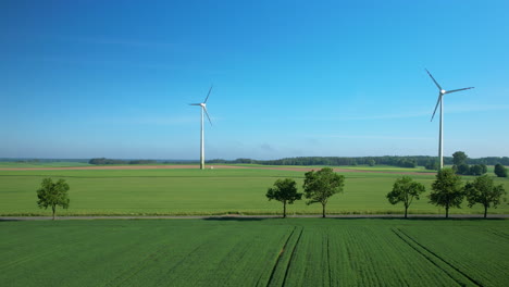 Movimiento-Aéreo-Hacia-Atrás-De-Las-Turbinas-Eólicas-En-El-Campo,-La-Carretera,-Los-árboles-Y-El-Paso-De-Automóviles