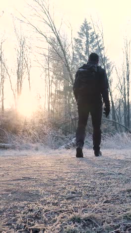 man hiking in a frozen forest at sunrise