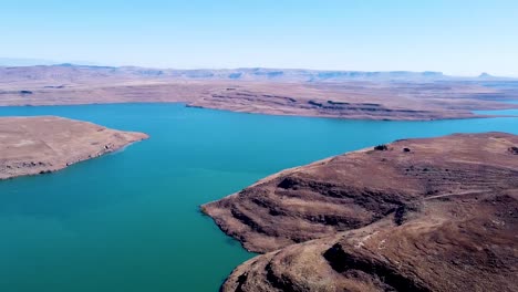 aerial drone shot panning around to reveal the beautiful blue water of the driefkloof dam, the dam surrounded by dry burnt veld, free state, south africa