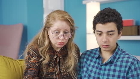 Young-man-looking-at-laptop-with-his-mother-at-home.