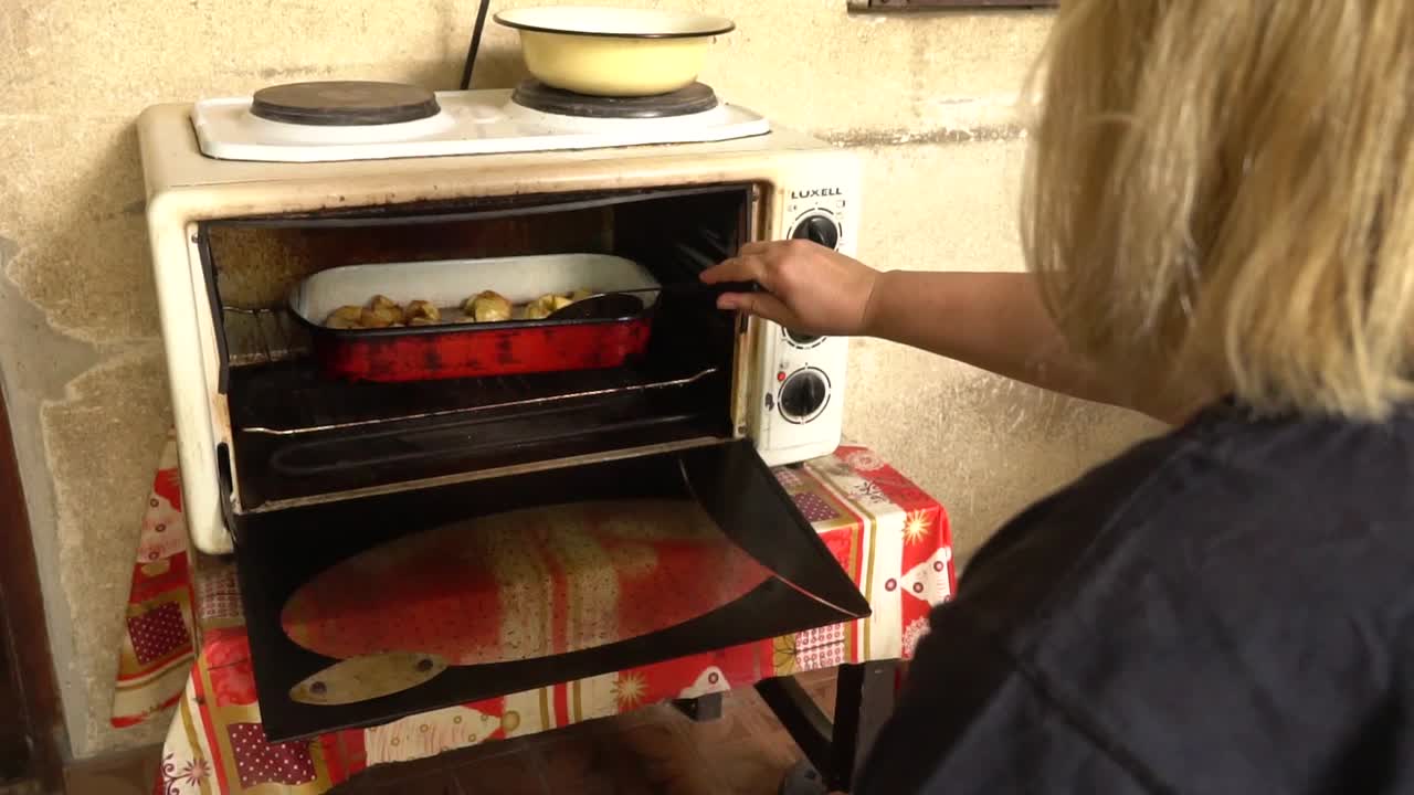 mujer rubia horneando delicioso plato en el horno