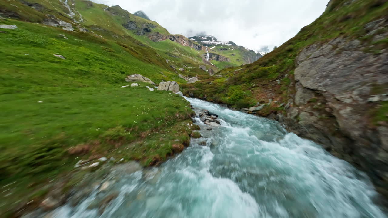 un arroyo de montaña corriendo bajo un pequeño puente de piedra en un valle verde y exuberante cerca de cervinia