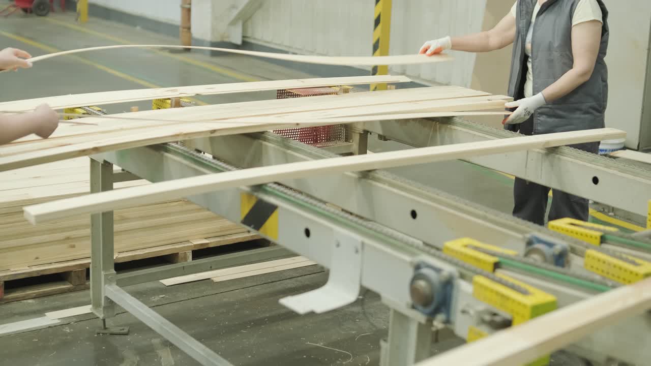 Workers Sorting Wooden Planks on a Conveyor Belt in a Factory
