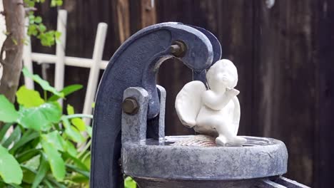 ceramic angel figurine sitting on top of a water pump in the rain