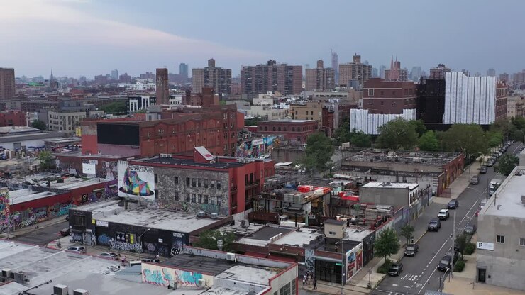 Aerial rise over the industrial Bushwick neighborhood of Brooklyn, New York revealing the Manhattan skyline in the distance