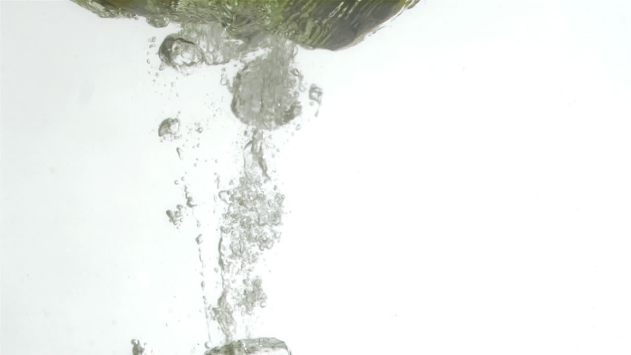 초록색 진주가 슈퍼 슬로 모션으로 물 속으로 떨어집니다.