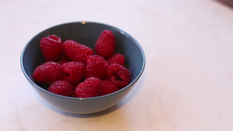 juicy red ripe raspberries in a blue bowl