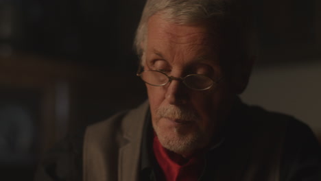 old passionate man writes a letter in his office at night
