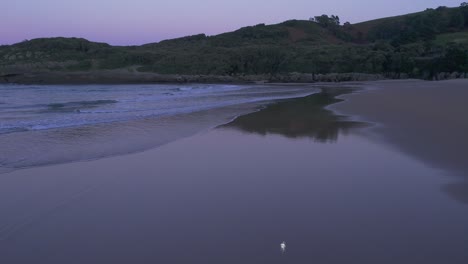 Las-Olas-Fluyen-En-Una-Playa-De-Arena-Aislada,-Reflejo-Del-Atardecer,-Costa-De-Cantabria,-España