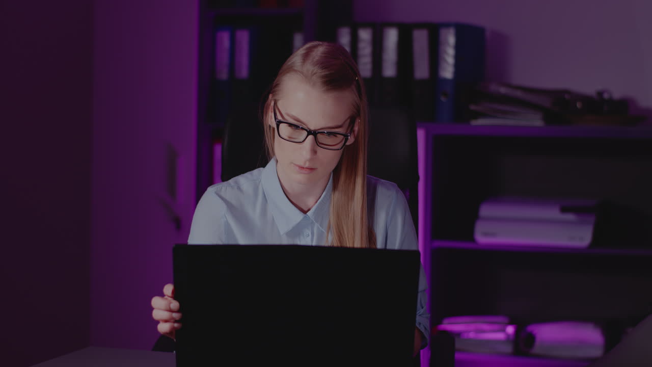 Woman working on laptop at night in office