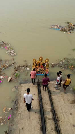 Drone view of immersion of idol of Hindu Goddess Durga in ganga river, garbage polluting river water