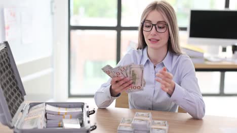 Woman counting large stacks of cash on a desk from a briefcase