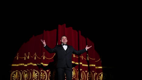 theatrical stage. man in costume appearing on a scene and presents the performance in light spot on dark background.