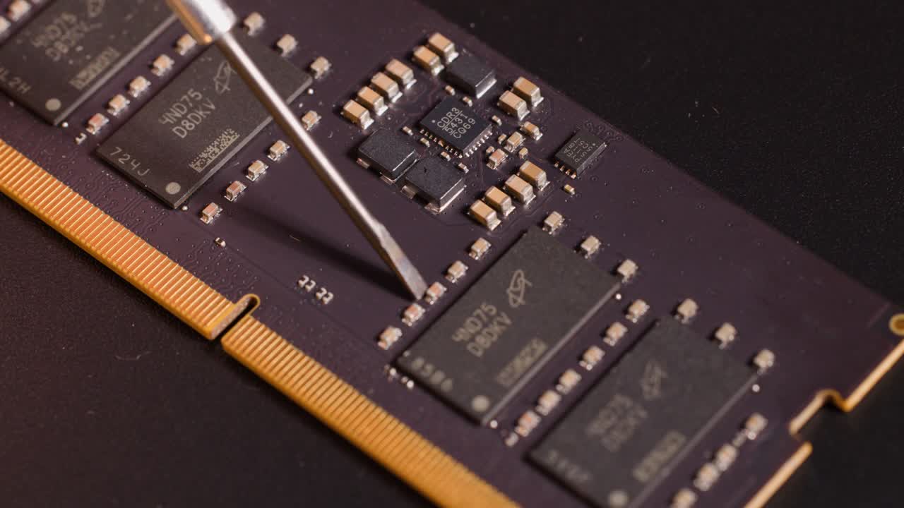 Close-up macro shot of a metal probe inspecting electronic components on a computer RAM stick