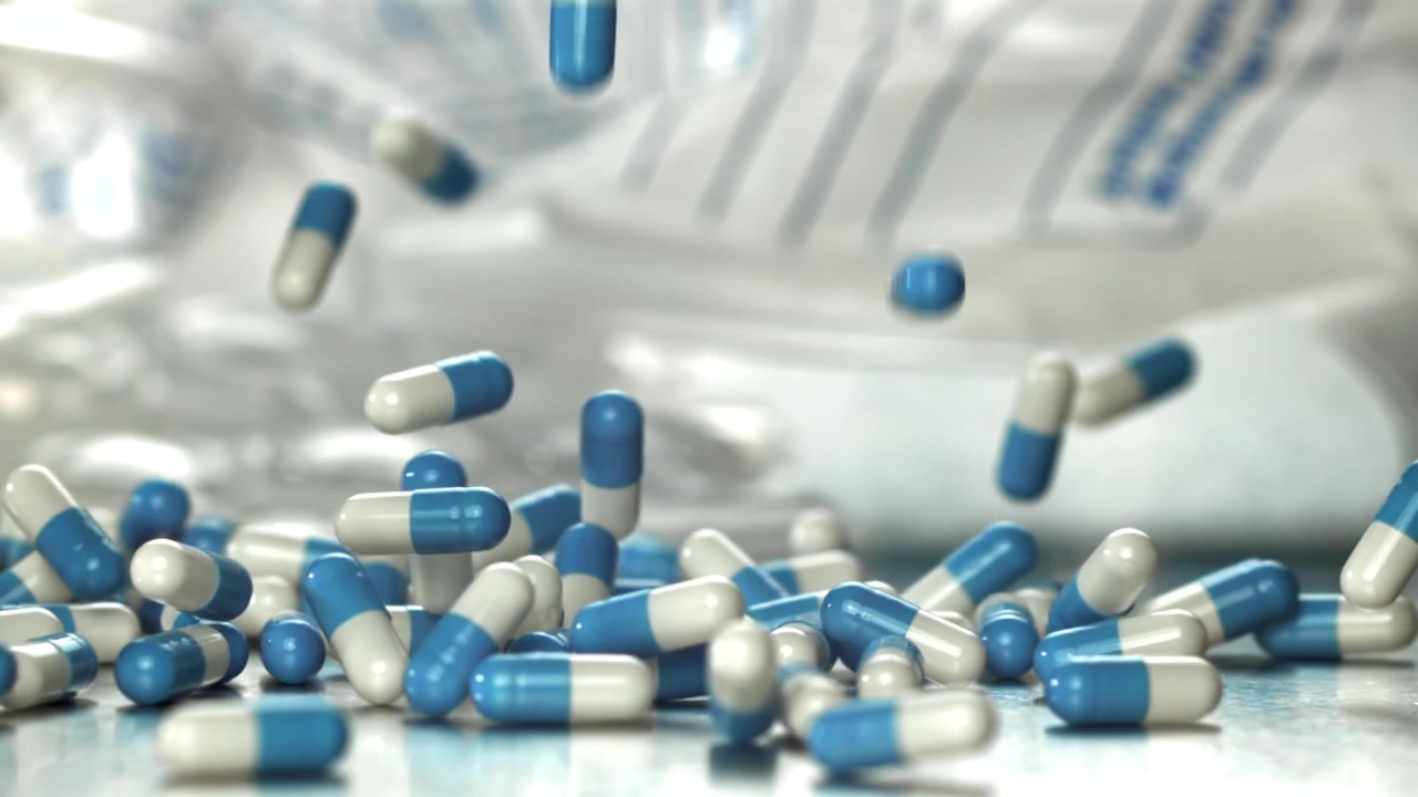 Capsule di medicinale blu e bianche che cadono al rallentatore