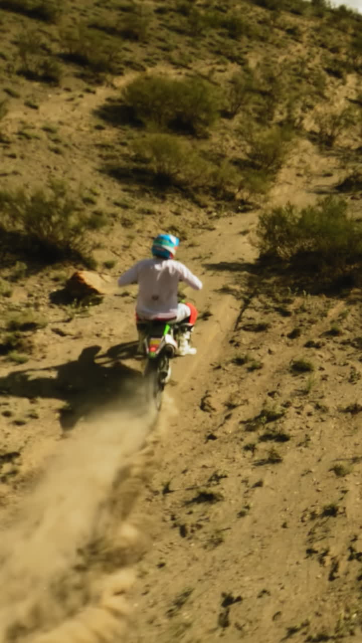 persona con casco monta motocicleta a lo largo de la colina boscosa fpv drone. deportista en motocicleta disfruta de carreras offroad en las tierras altas del desierto. concurso de deporte de moto