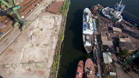 Aerial-descending-view-to-dockyard-ship-in-freight-shipping-harbour-next-to-large-green-Gdansk-heavy-cranes