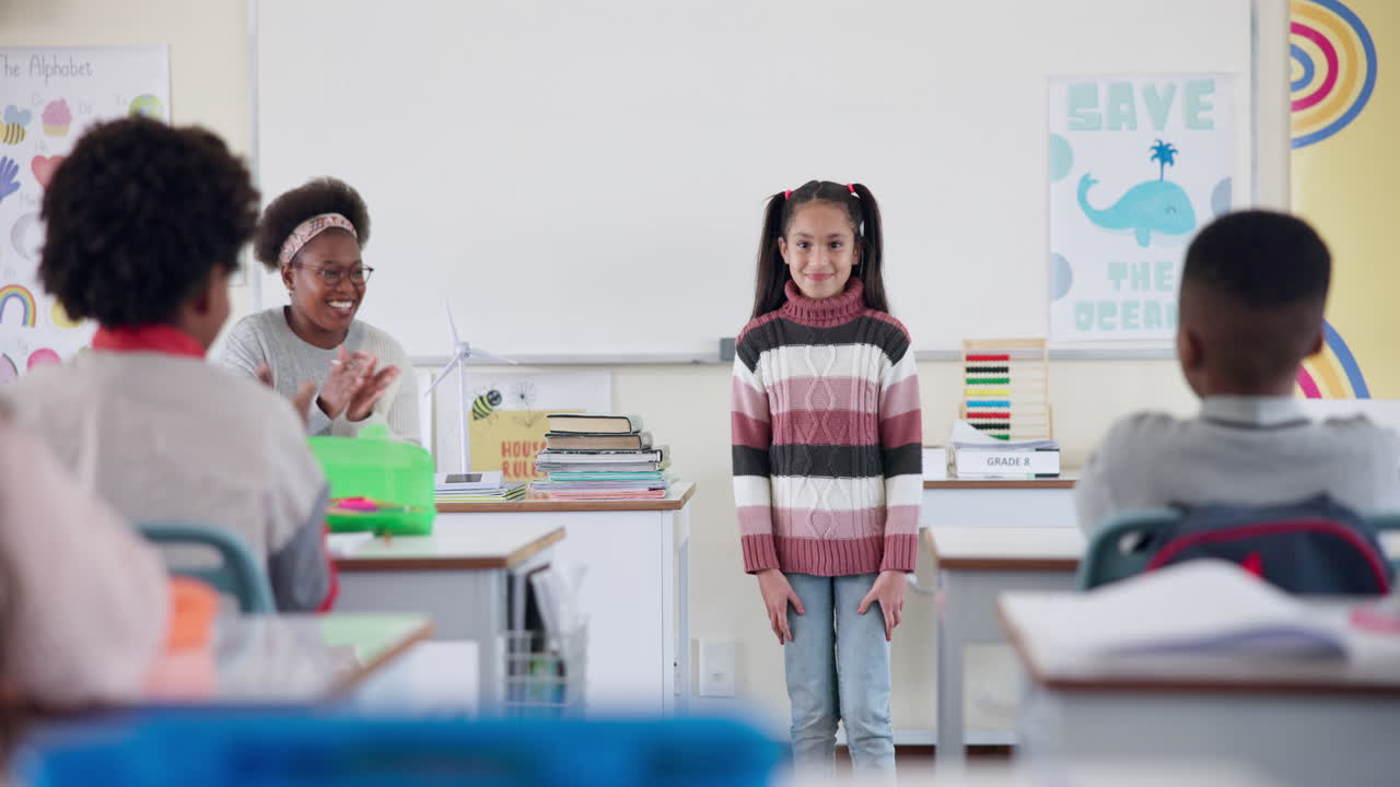 Girl standing in front of class with teacher and students