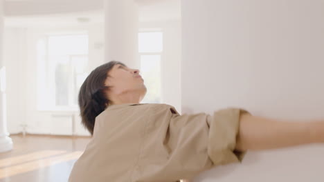 close up view of contemporary male japanese dancer training dance moves leaning on a column in the studio