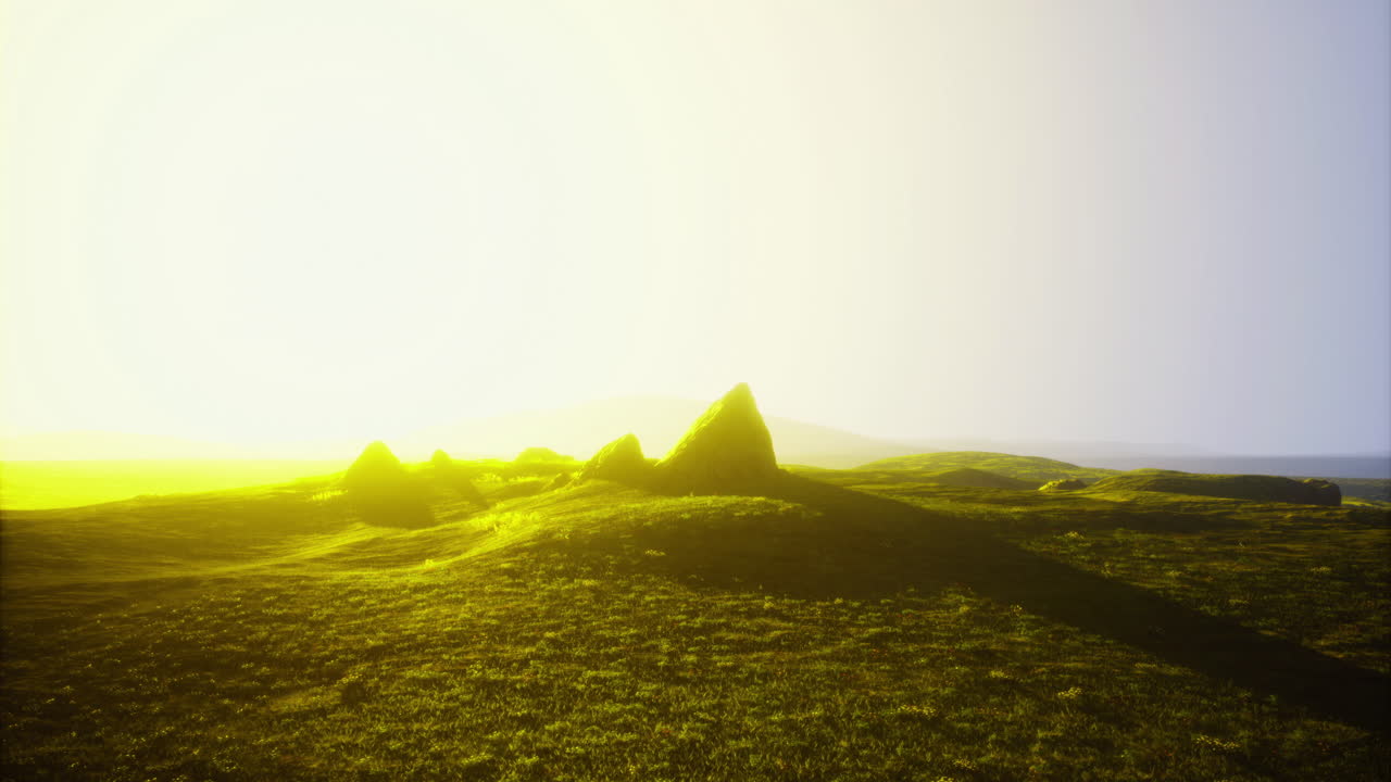 Sunrise over grassy hills and pyramidal mounds in a serene rural landscape