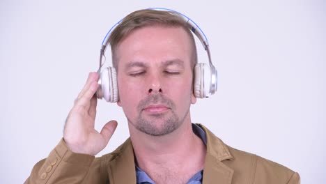 face of happy mature businessman listening to music