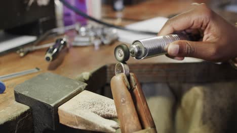 biracial female worker shaping ring using handcraft tools in workshop in slow motion