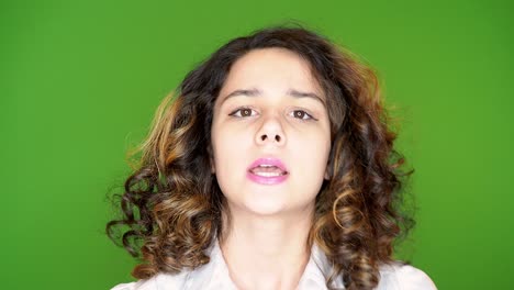 hermosa joven de cabello oscuro excitada en una blusa blanca hablando con la cámara en una pantalla verde. 4k