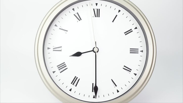 Time lapse silver wall clock tells the time at 9o'clock.