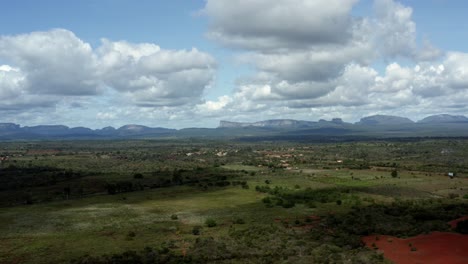 beautiful left trucking aerial drone shot of green fields with huge plateaus in the background of the chapada diamantina national park in bahia, northeastern brazil on a warm sunny summer day