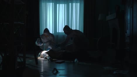 young diverse forensic team examining dead body at crime scene bottom view shot of young african american male forensic expert in protective suit unzipping black body bag with caucasian female colleague taking photo of victim on camera working in team together