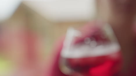 close up of glasses filled with red iced drinks held during toast by people in soft focus, capturing joyful moment and celebration in warm ambient light with water droplets on glass surface