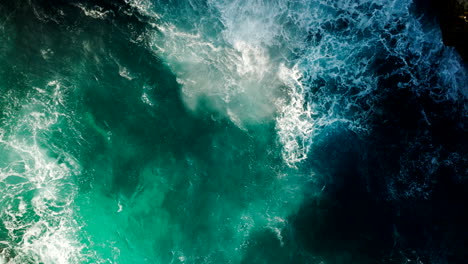 waves splash and spray against rocky arch of devil's tears, lembongan, top drone