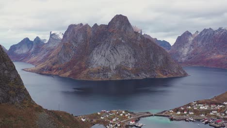 steep mountains rise up from the sea to surround small flat islands with fishing villages in lofoten, norway