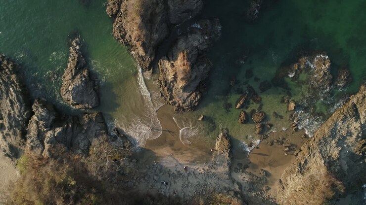 Ripresa aerea dall'alto in ascesa su una piccola insenatura rocciosa in una bellissima spiaggia tropicale, 4K