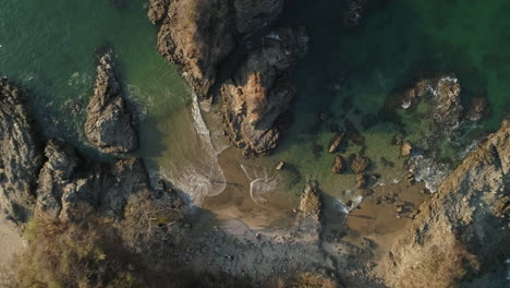 rising top down aerial over small rocky inlet on beautiful tropical beach, 4k