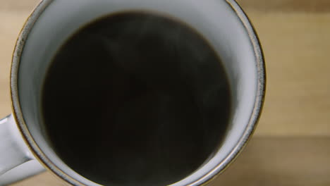 Pan-Dejó-Una-Taza-Humeante-De-Café-Negro-Sobre-Una-Mesa-De-Madera,-60-Fps