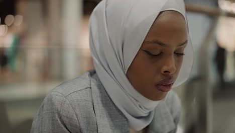 worried black lady with hijab looks aside in shopping mall