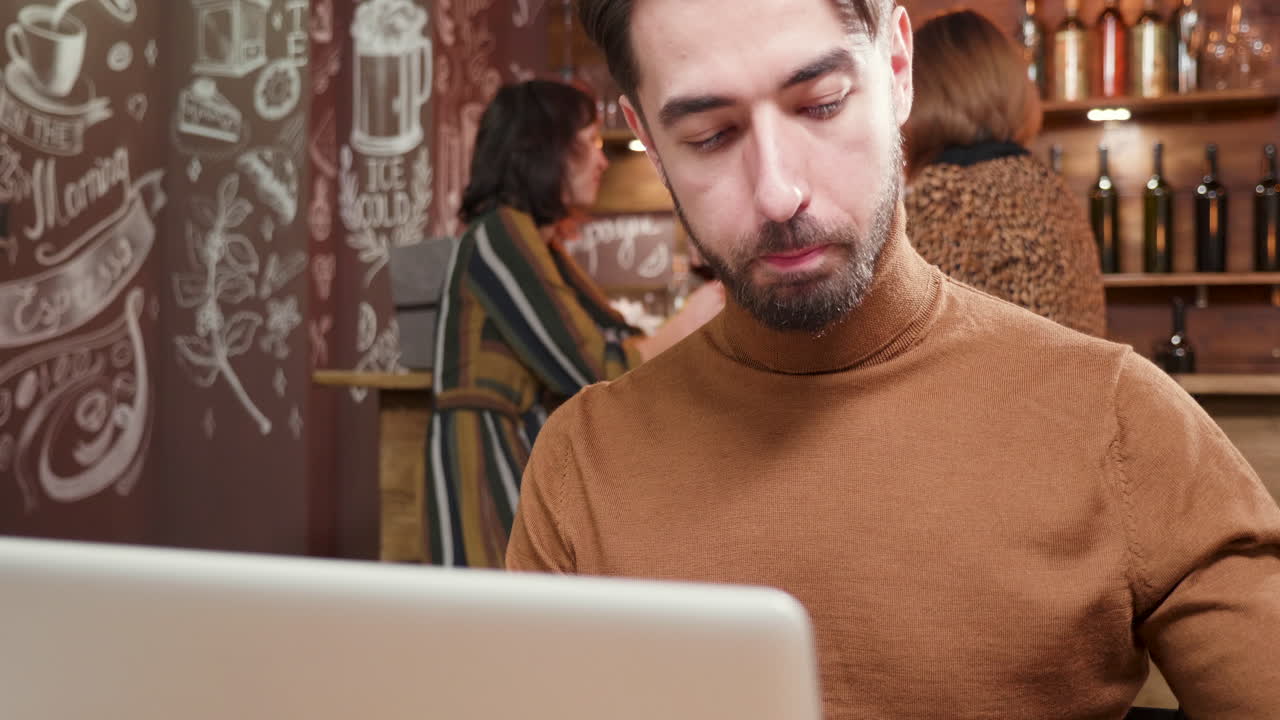 hombre trabajando en una computadora portátil en un café