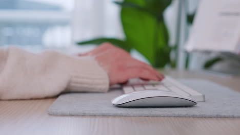 closeup of wireless mouse and keyboard on desk with female hands typing