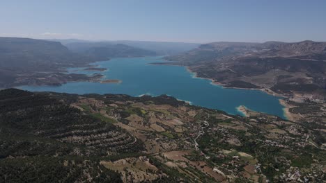 aerial-drone-view-of-the-lake-in-the-forest,-hills-and-mountains-with-a-forest-beside-the-lake,-the-natural-landscape-under-a-cloudy-sky