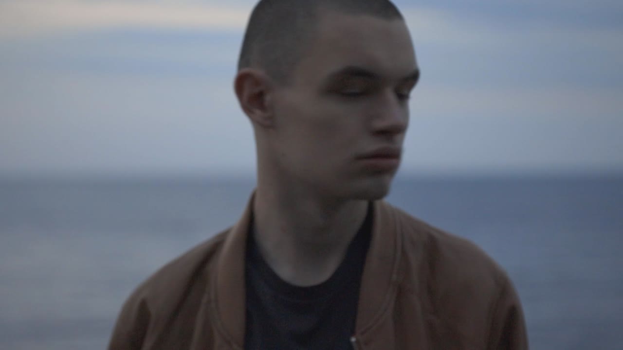 Serious Looking Man Turning Head On Both Sides Isolated On Opaque Blue Sea Background - Closeup Shot