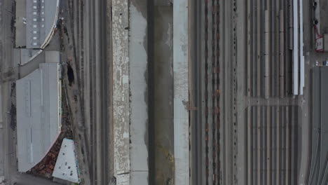 AERIAL:-Overhead-,-Birds-Eye-View-on-Los-Angeles-River-with-Water-on-Cloudy-Overcast-Sky-next-to-Train-Tracks