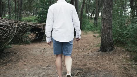 man walking next to man made structures in the forest