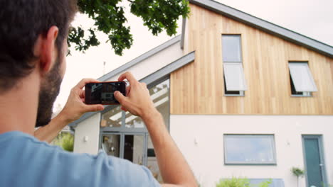 a man taking photos of his house from the outside