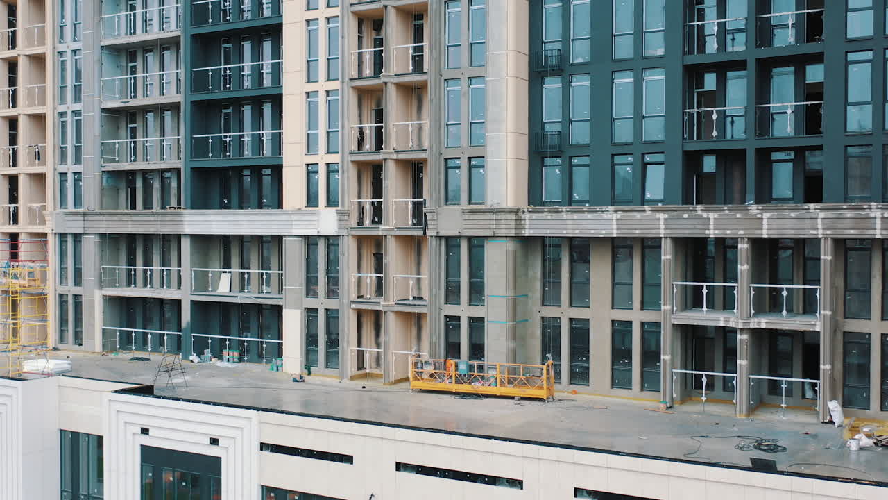 Tall apartment building. Construction of a multi-storey apartment building with windows and balconies. Camera rising up.