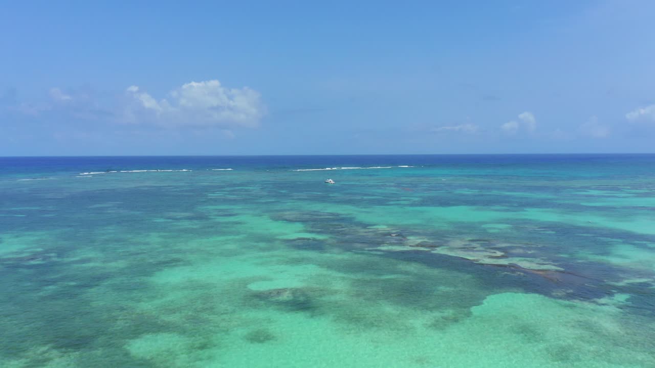 sensacional vuelo panorámico sobre el mar turquesa del océano hacia un solo bote de motor anclado en el agua en un día soleado, cap cana, república dominicana, enfoque aéreo superior
