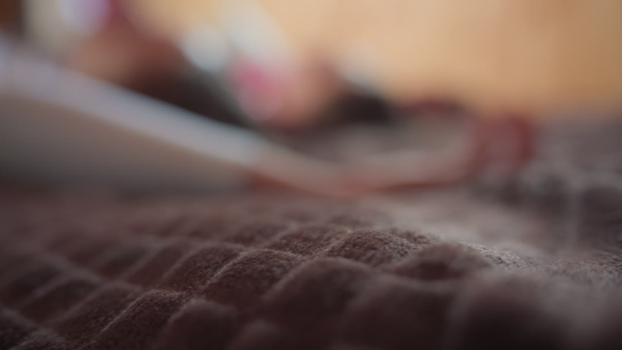 close up quilted brown bedspread with visible texture and soft focus as figures gently collapse onto bed, capturing dynamic movement, tactile surface